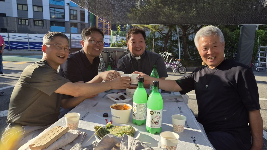 태릉성당 열린마당에서 성직자와 마을 주민들이 막걸리잔을 맞대며 이야기를 나누고 있다.